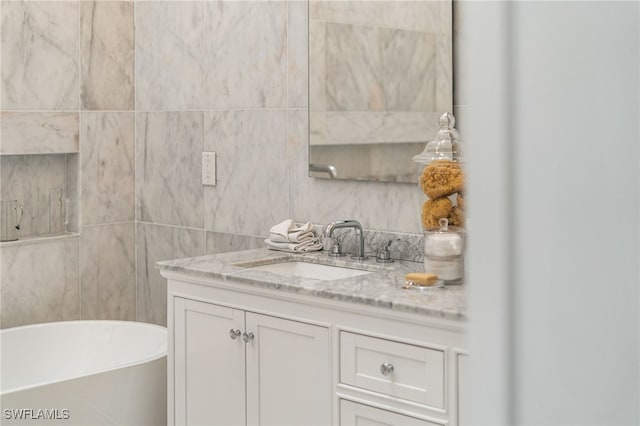 bathroom with tile walls, vanity, and a bathtub