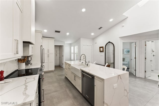 kitchen featuring sink, light stone counters, dishwasher, and a kitchen island with sink