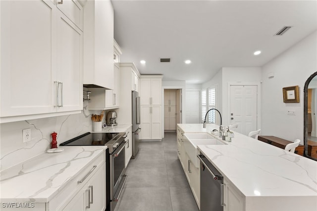 kitchen featuring appliances with stainless steel finishes, white cabinetry, sink, and light stone counters