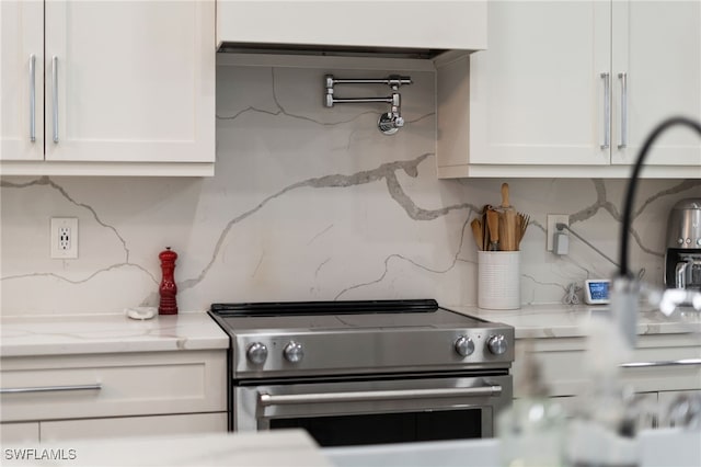 kitchen with stainless steel range with electric stovetop, decorative backsplash, white cabinets, and light stone counters