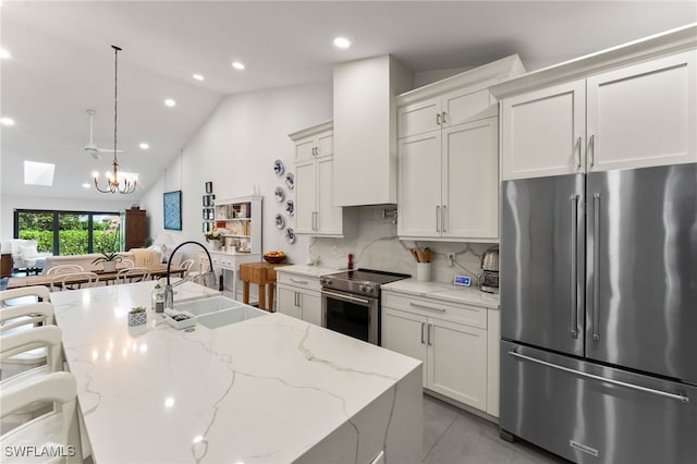 kitchen featuring hanging light fixtures, backsplash, appliances with stainless steel finishes, lofted ceiling with skylight, and sink