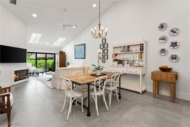 dining area featuring ceiling fan with notable chandelier, high vaulted ceiling, and a skylight