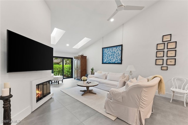 living area with high vaulted ceiling, a glass covered fireplace, recessed lighting, finished concrete floors, and a skylight
