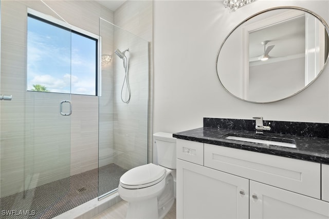 bathroom with vanity, toilet, a shower with shower door, and ceiling fan