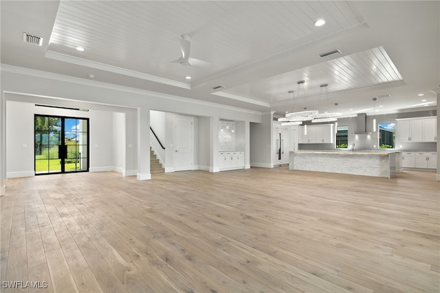 unfurnished living room with crown molding, a tray ceiling, light wood-type flooring, and ceiling fan