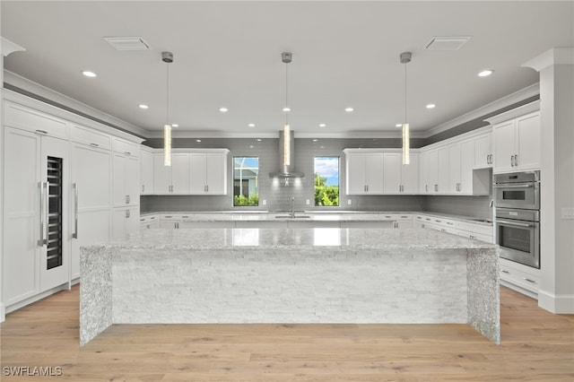 kitchen featuring a spacious island, white cabinets, light stone countertops, and stainless steel double oven