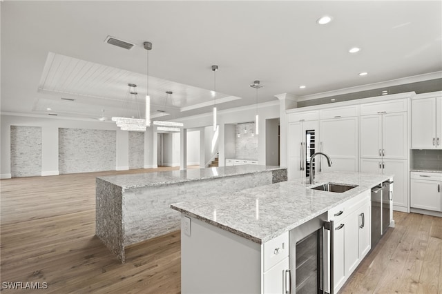 kitchen featuring sink, hanging light fixtures, a large island, white cabinetry, and beverage cooler