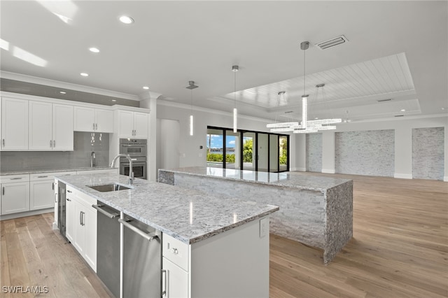 kitchen featuring a spacious island, light hardwood / wood-style flooring, white cabinetry, and decorative light fixtures