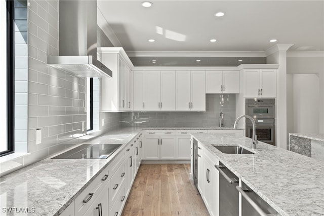 kitchen with light stone counters, backsplash, white cabinetry, wall chimney exhaust hood, and stainless steel appliances