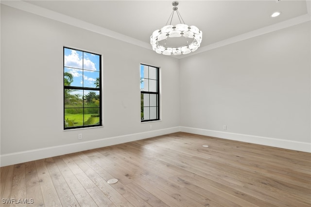 empty room featuring light hardwood / wood-style flooring, a chandelier, and crown molding