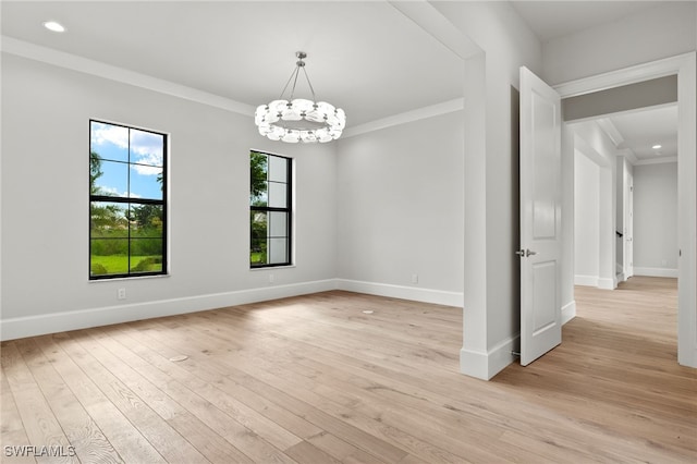 empty room featuring an inviting chandelier, ornamental molding, and light wood-type flooring