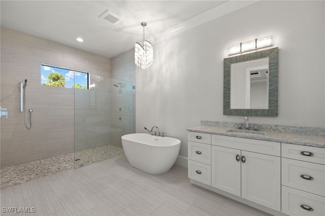 bathroom featuring vanity, a chandelier, and plus walk in shower