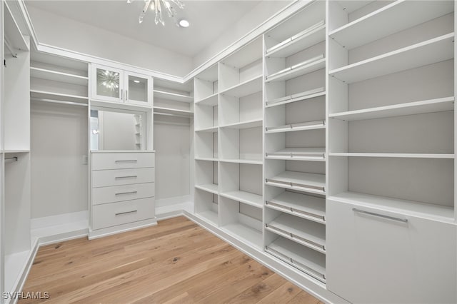 walk in closet featuring an inviting chandelier and light wood-type flooring