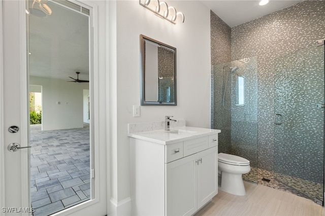 bathroom with vanity, an enclosed shower, toilet, and ceiling fan