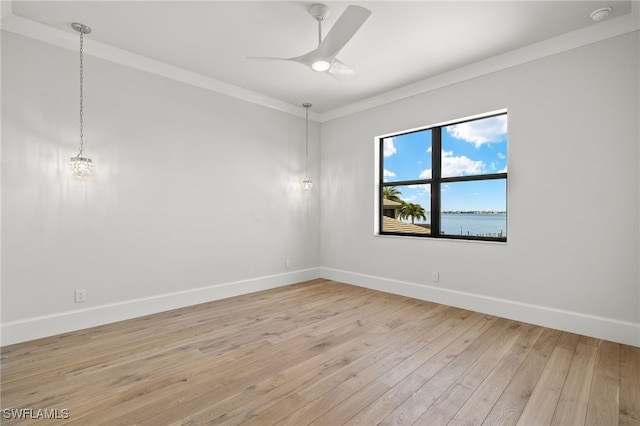 spare room with a water view, light hardwood / wood-style floors, crown molding, and ceiling fan