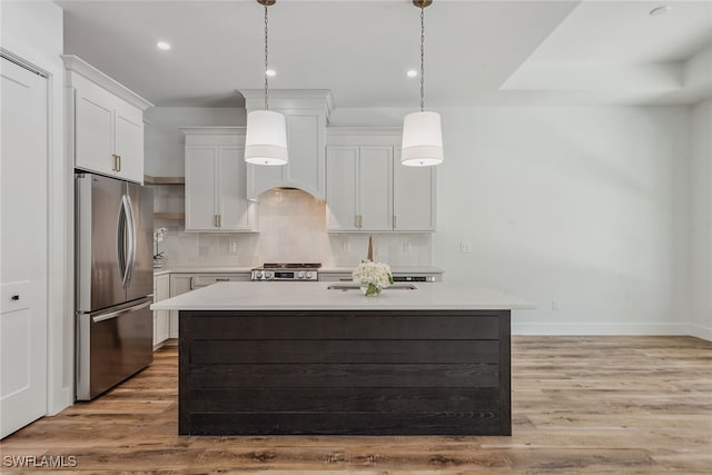 kitchen featuring white cabinetry, light wood-type flooring, stainless steel appliances, and decorative light fixtures