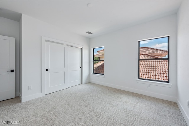 unfurnished bedroom with light carpet and a closet