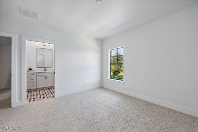 unfurnished bedroom featuring ensuite bath and light carpet