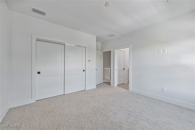 unfurnished bedroom with a closet and light colored carpet