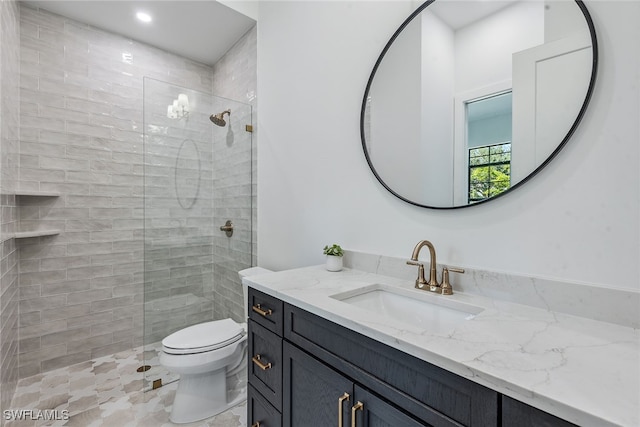 bathroom with vanity, toilet, and a tile shower