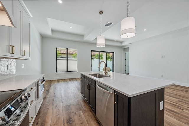 kitchen featuring light stone counters, stainless steel appliances, sink, light hardwood / wood-style floors, and white cabinets