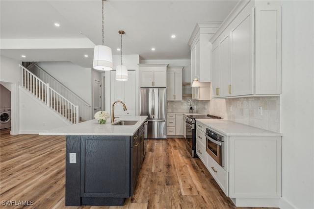 kitchen featuring sink, a kitchen island with sink, white cabinetry, light wood-type flooring, and appliances with stainless steel finishes