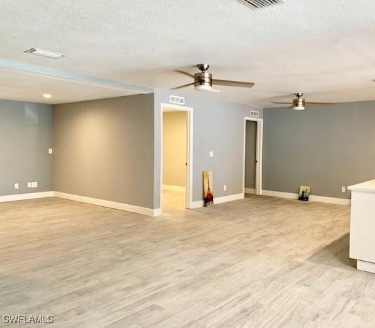 basement featuring ceiling fan, a textured ceiling, and light hardwood / wood-style flooring