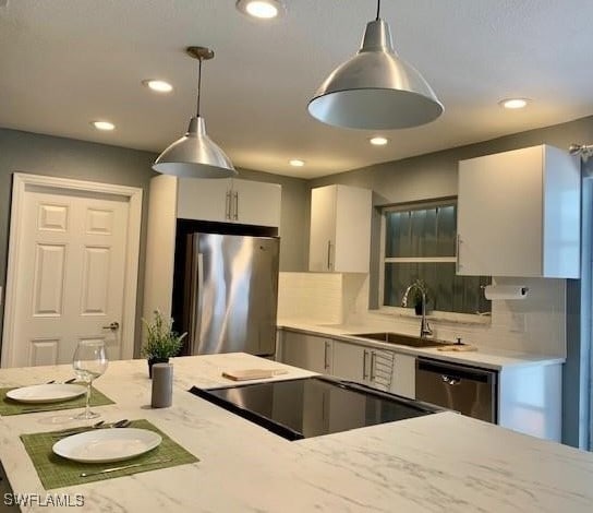 kitchen featuring backsplash, white cabinetry, sink, pendant lighting, and stainless steel appliances