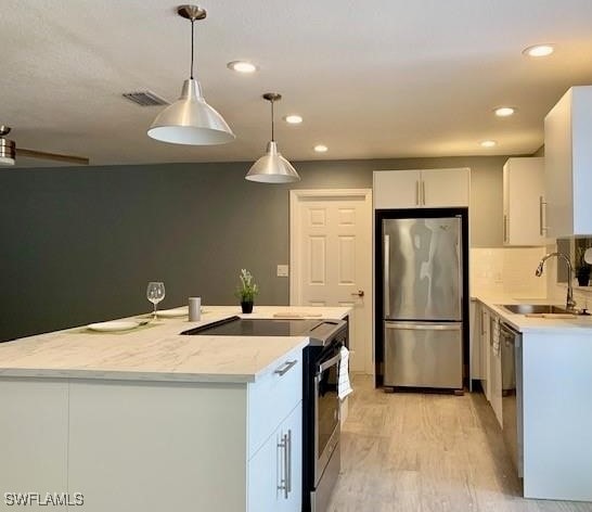 kitchen with a kitchen island, white cabinetry, sink, pendant lighting, and stainless steel appliances