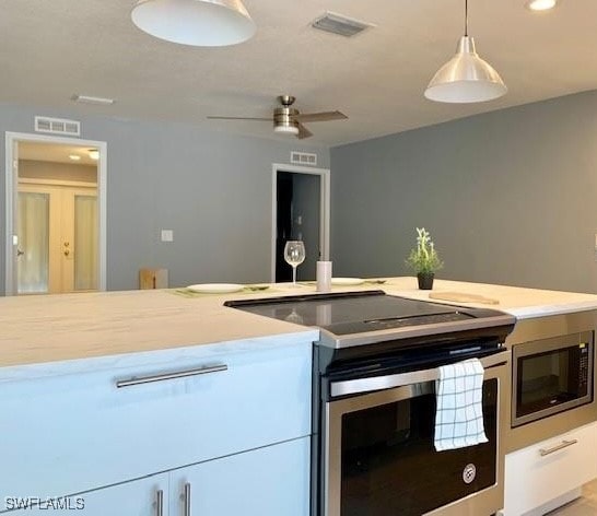 kitchen featuring appliances with stainless steel finishes, pendant lighting, white cabinets, and ceiling fan