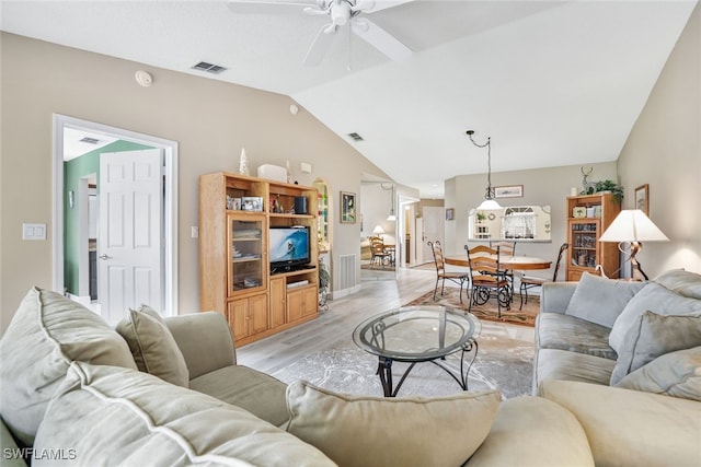 living room featuring ceiling fan, lofted ceiling, and light hardwood / wood-style flooring