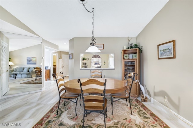 dining area featuring vaulted ceiling and light wood-type flooring