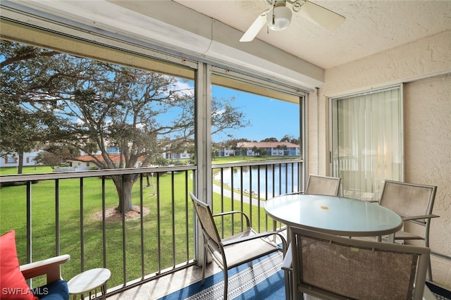 sunroom / solarium with a water view and ceiling fan