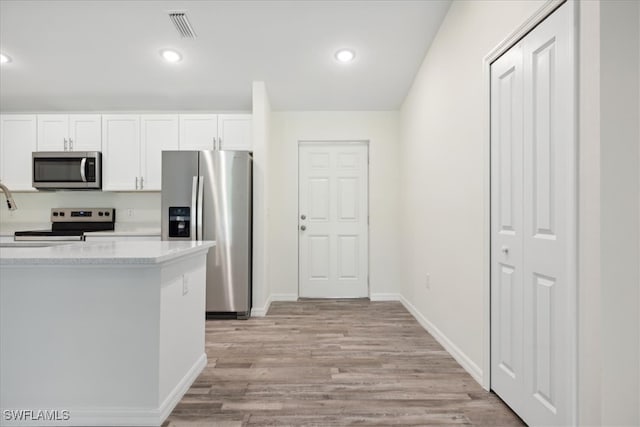 kitchen featuring appliances with stainless steel finishes, light hardwood / wood-style floors, and white cabinets