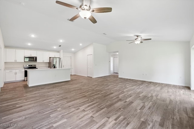 kitchen with appliances with stainless steel finishes, vaulted ceiling, ceiling fan, and light hardwood / wood-style flooring