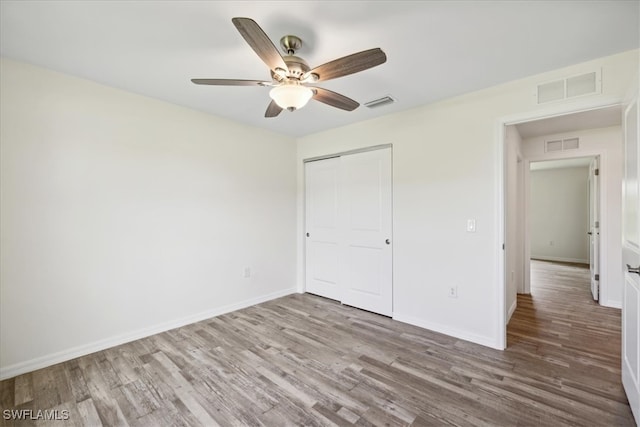 unfurnished bedroom featuring a closet, wood-type flooring, and ceiling fan