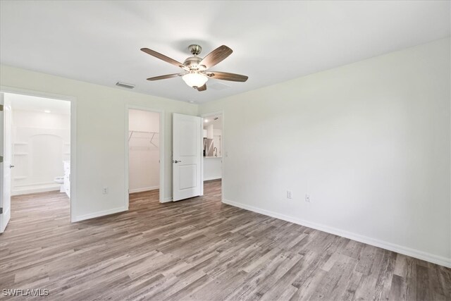 unfurnished bedroom featuring ceiling fan, a closet, light hardwood / wood-style floors, and a spacious closet