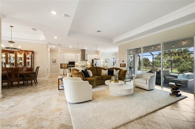 living room featuring a notable chandelier, ornamental molding, and a tray ceiling