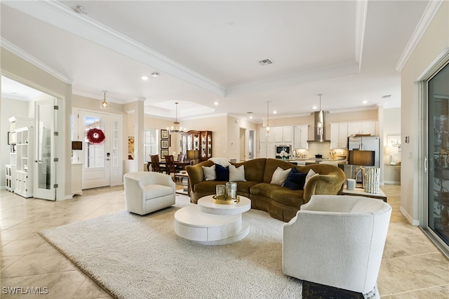 living room featuring a notable chandelier, light tile patterned floors, crown molding, and a tray ceiling