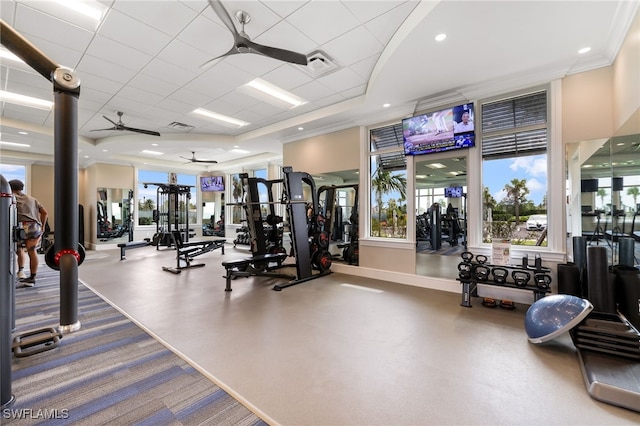 gym with a drop ceiling, a tray ceiling, ceiling fan, and ornamental molding