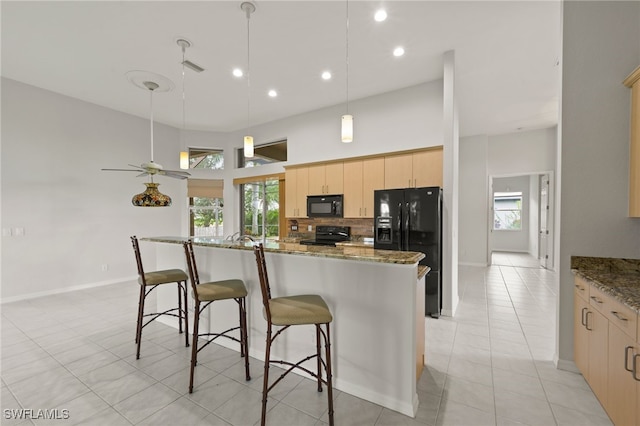 kitchen with ceiling fan, dark stone countertops, light brown cabinets, and black appliances