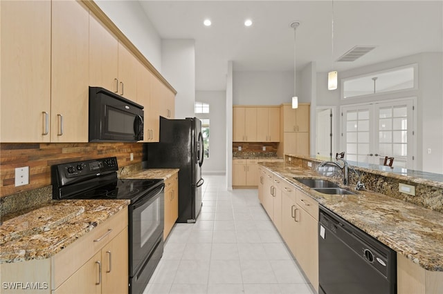 kitchen featuring light brown cabinetry, decorative light fixtures, sink, and black appliances