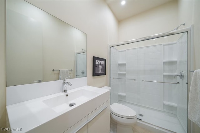 bathroom featuring vanity, a shower with shower door, and toilet