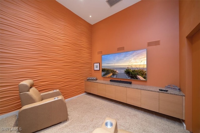 home theater room featuring a towering ceiling and light colored carpet