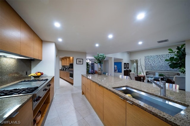 kitchen featuring decorative backsplash, dark stone countertops, light tile patterned floors, stainless steel appliances, and sink