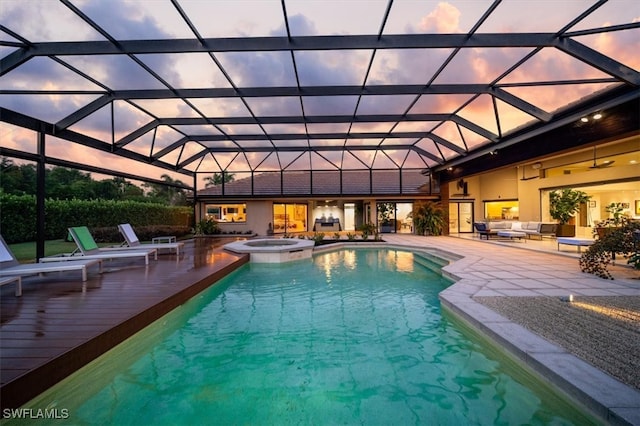 pool at dusk featuring an in ground hot tub, a lanai, and a patio area