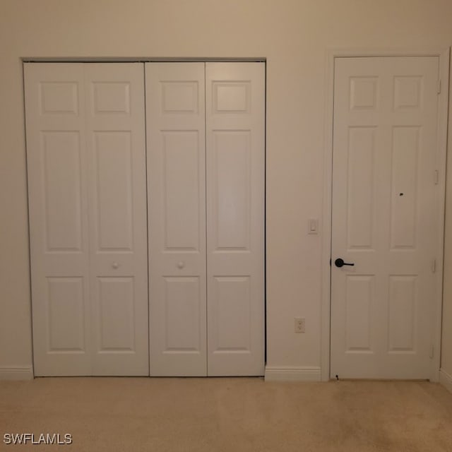 unfurnished bedroom with light carpet and a closet