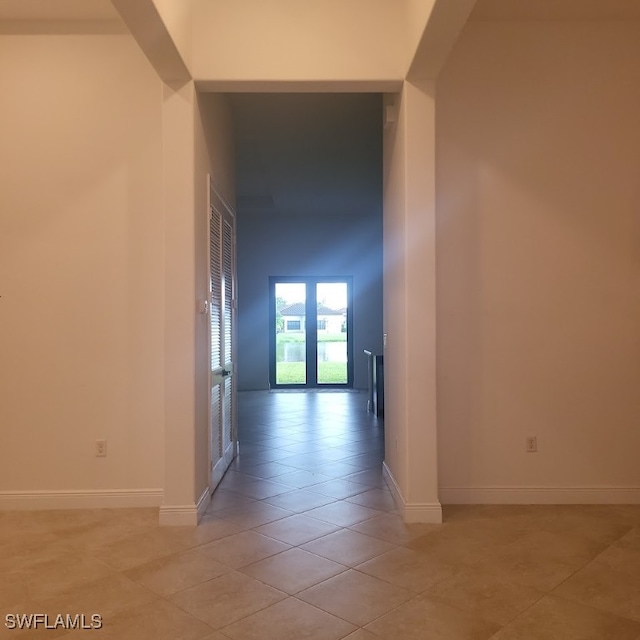 hall featuring light tile patterned flooring and a high ceiling