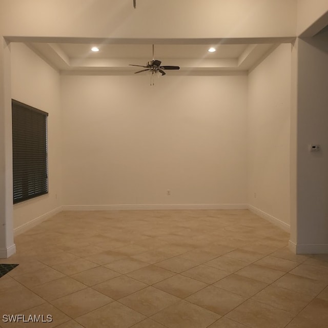 spare room with ceiling fan and a raised ceiling