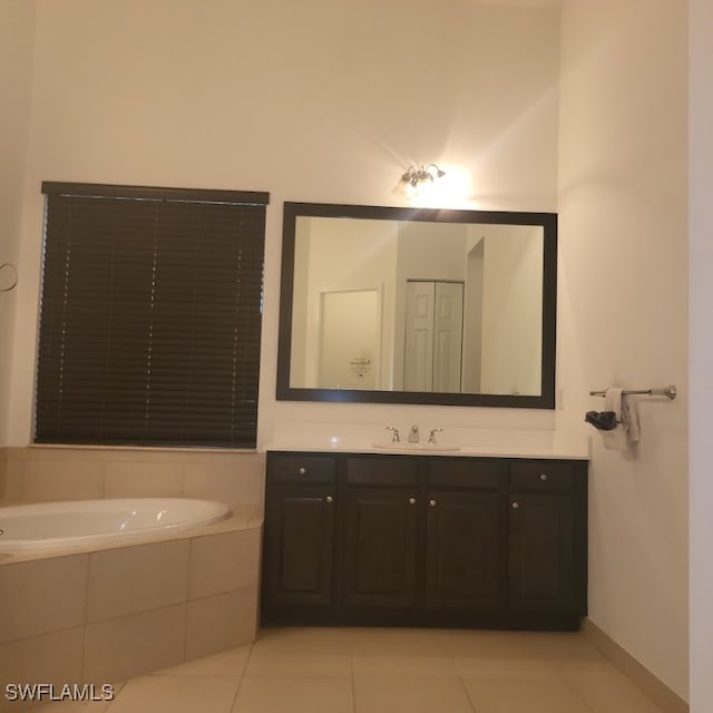 bathroom featuring tiled tub, vanity, and tile patterned floors